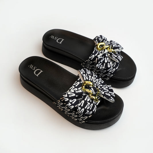 Nolva women’s black slide sandal with oversized printed bow and gold chain buckle—cushioned flat for casual wear.
